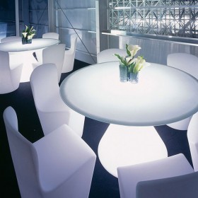 Illuminated round ED light table with white chairs and decorative flowers