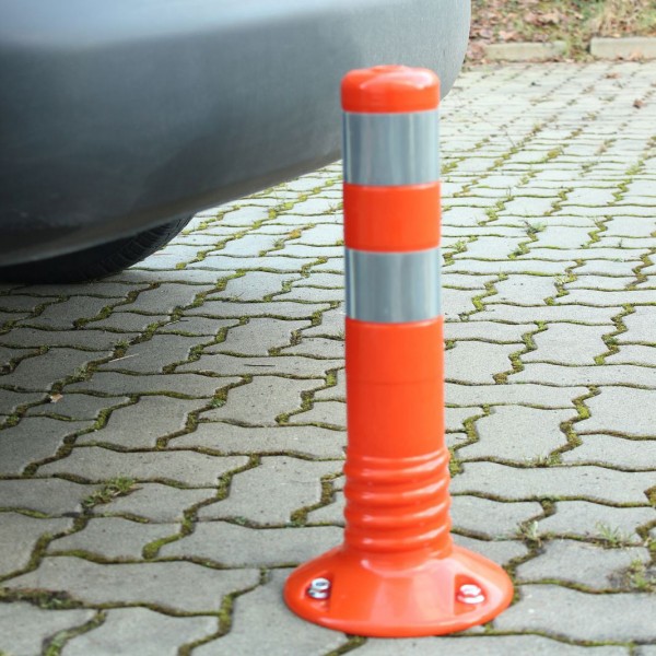 Orange reflective flexible stanchion fixed to ground in front of car on paving