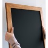 Pizarra con marco de madera sostenida en mano, esquina superior del panel negro