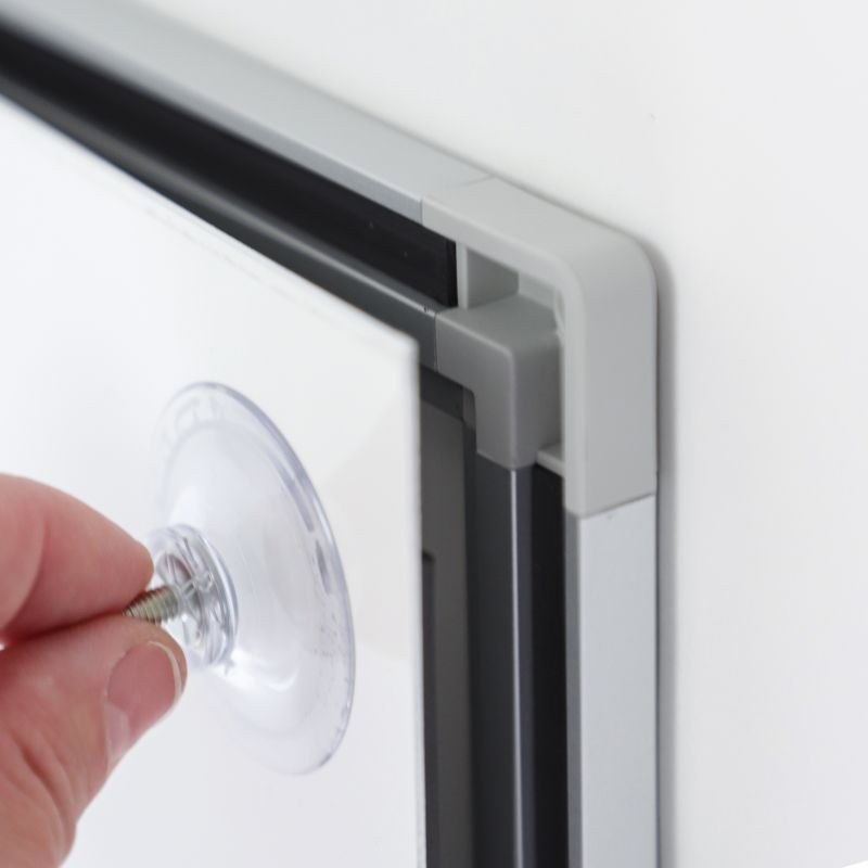 Close-up of the aluminium frame and magnetic strip of the Signcode® Slim panel, removing the plate with a suction cup