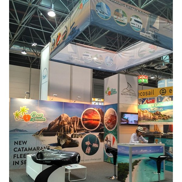 Exhibit sign ECO quadratisch über Messestand mit Katamaranmotiven installiert